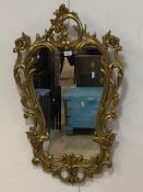A Rococo style gilt framed wall hanging mirror, the frame of cartouche form decorated with scrolling