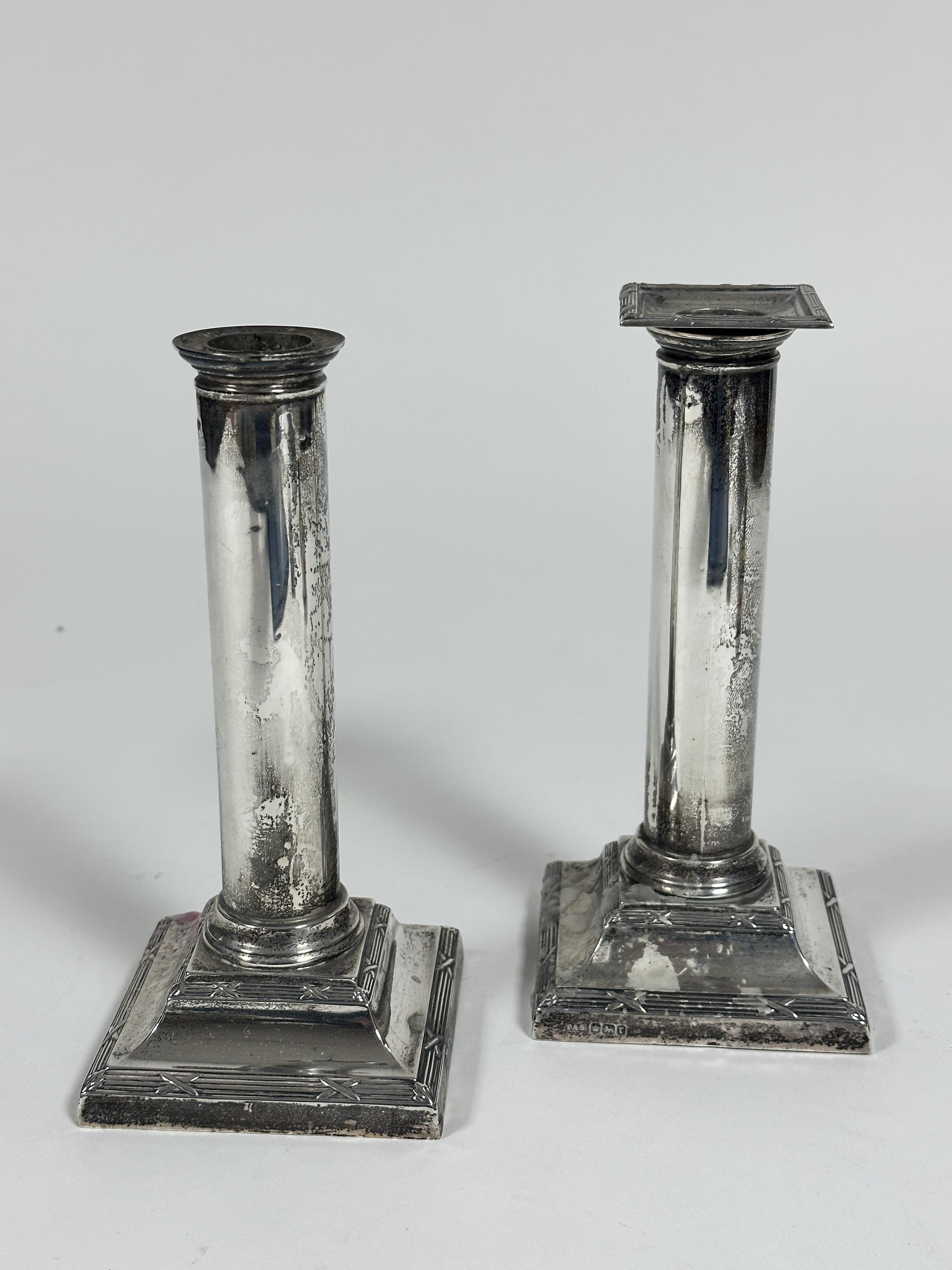 A pair of Edwardian Sheffield silver cast candlesticks of column form on stepped bases with reeded