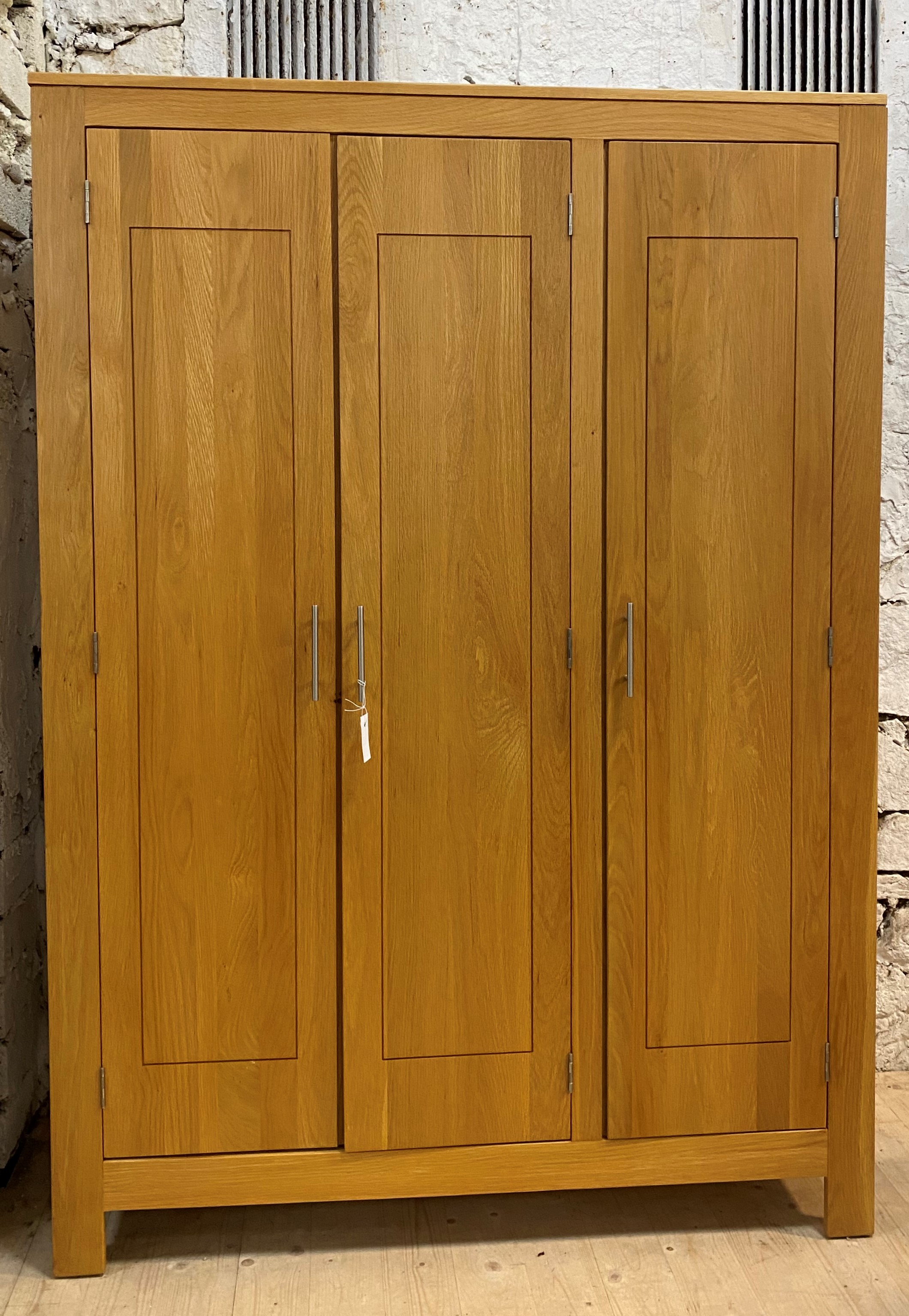 A contemporary light hardwood triple wardrobe, the interior fitted with shelves and for hanging,