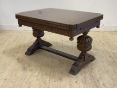 A carved oak duo draw leaf extending dining table, the frieze carved with vining leaves and berries,