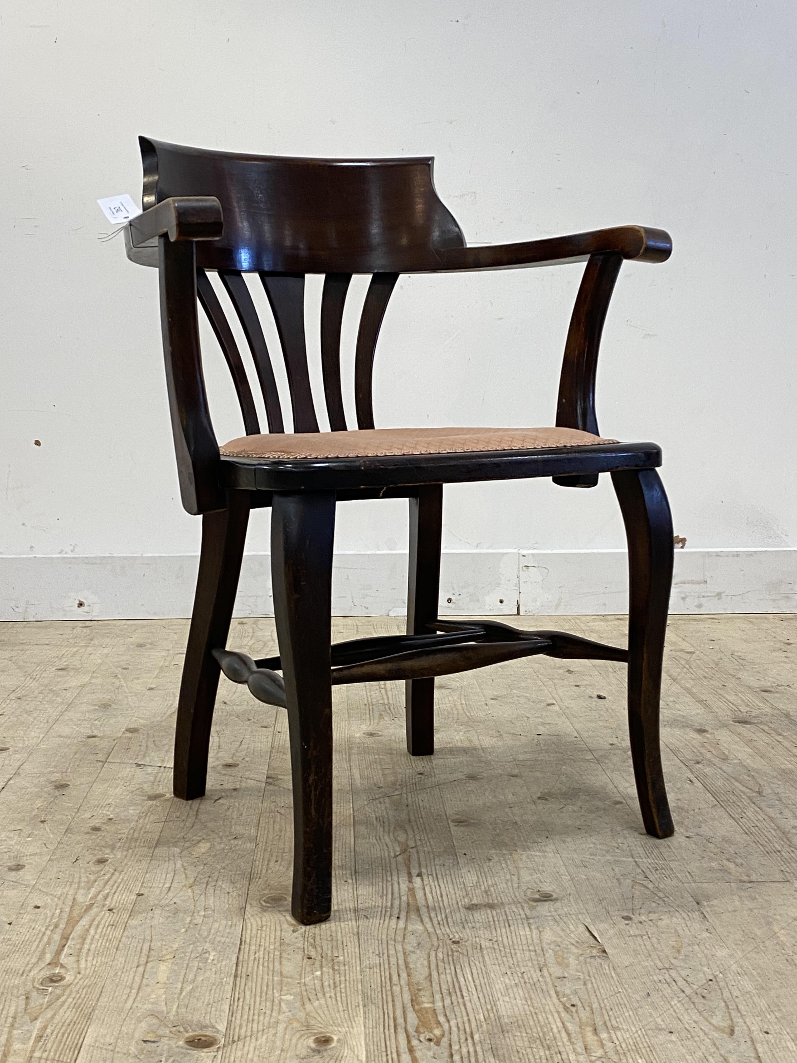 An early 20th century stained beech desk chair, the pierced splat back and open arms with scrolled