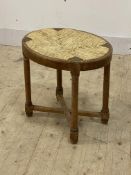 An early 20th century limed oak stool with string seat, raised on turned supports united by a