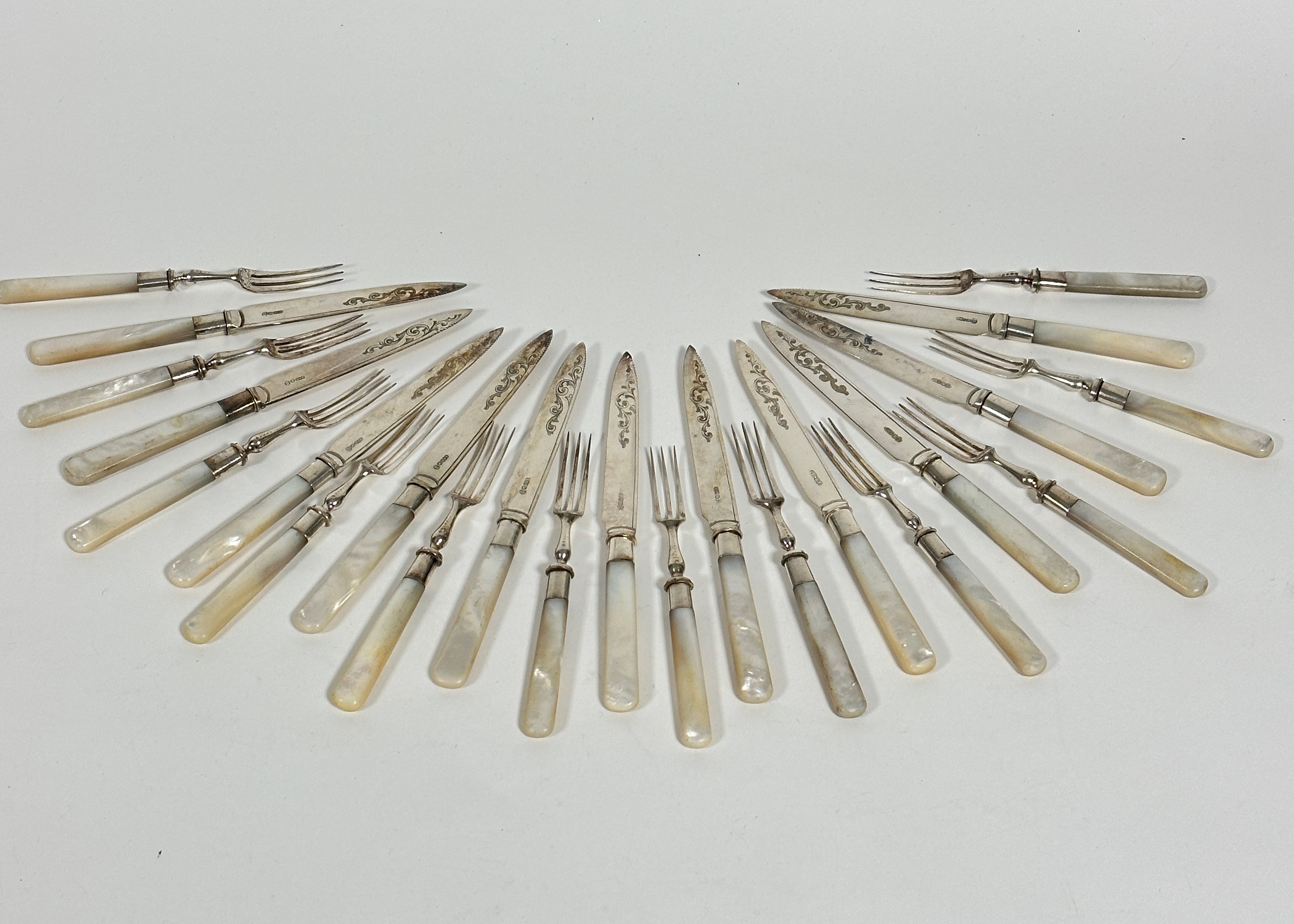 Twelve pairs of mother of pearl handled Epns engraved fruit knives and forks, (L: 18.5c)