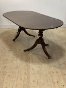 A Regency style brass inlaid mahogany twin pillar dining table, moving on hairy paw cast brass
