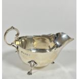 A Birmingham 1934 silver George III style scalloped sauce boat with C scroll handle raised on