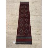 A Meshwani runner rug, the red field with repeating lozenges 253cm x 60cm