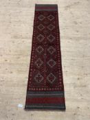 A Meshwani runner rug, the red field with repeating lozenges 253cm x 60cm