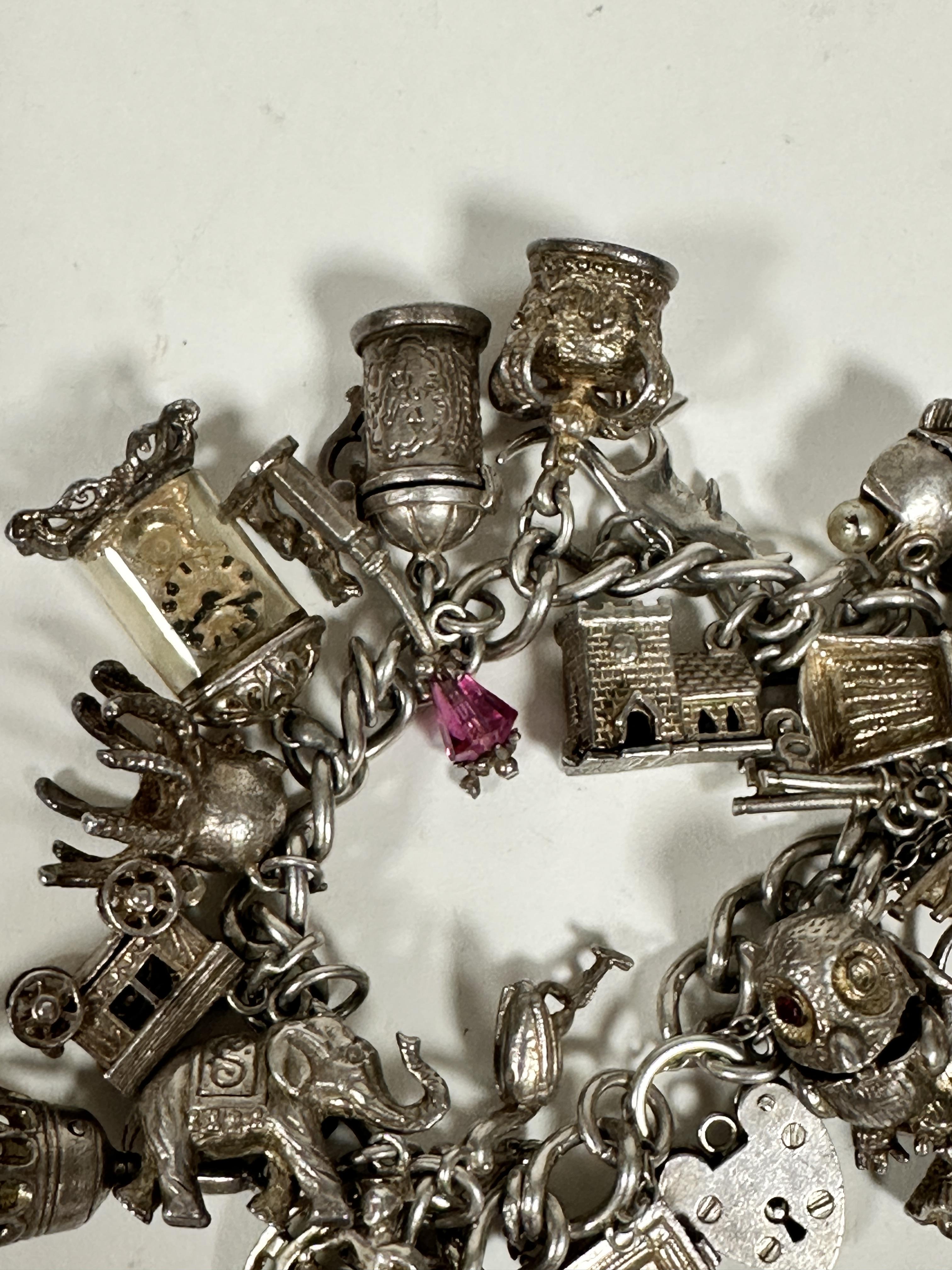 A silver curb link bracelet mounted with a large collection of silver charms including a key, bells, - Image 4 of 4