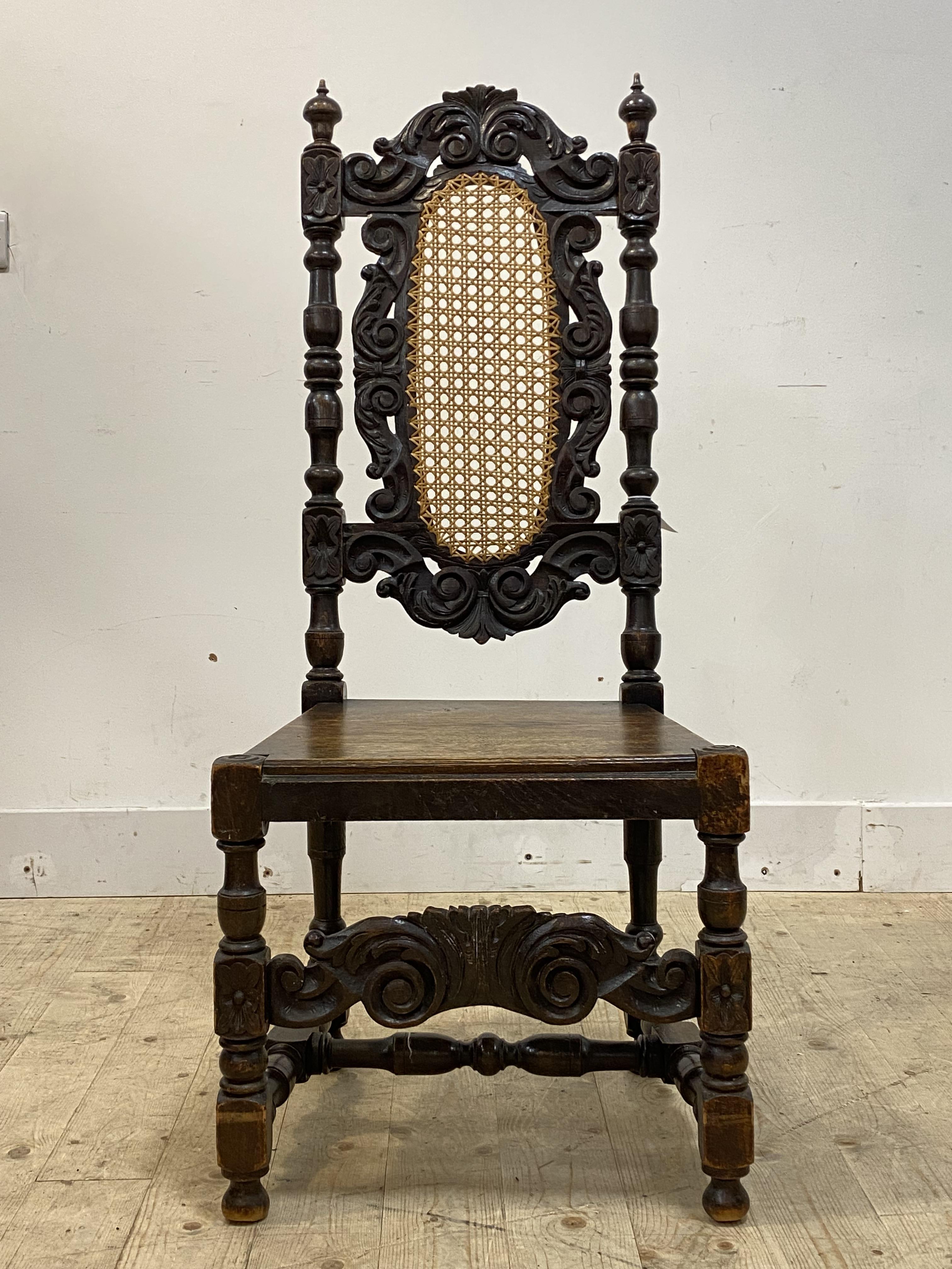 A 19th century stained oak high back chair of Carolean design, with floral carved and cane