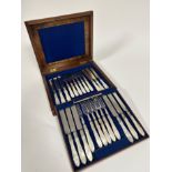 A Victorian walnut case, top slight split, containing twelve pairs of Epns mother of pearl handled