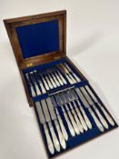 A Victorian walnut case, top slight split, containing twelve pairs of Epns mother of pearl handled