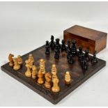 An African hardwood chess board with relief carved leaf border complete with stained ebony and beech