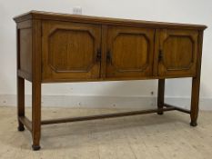 An early 20th century dresser base, fitter with three panelled doors, raised on fluted supports,