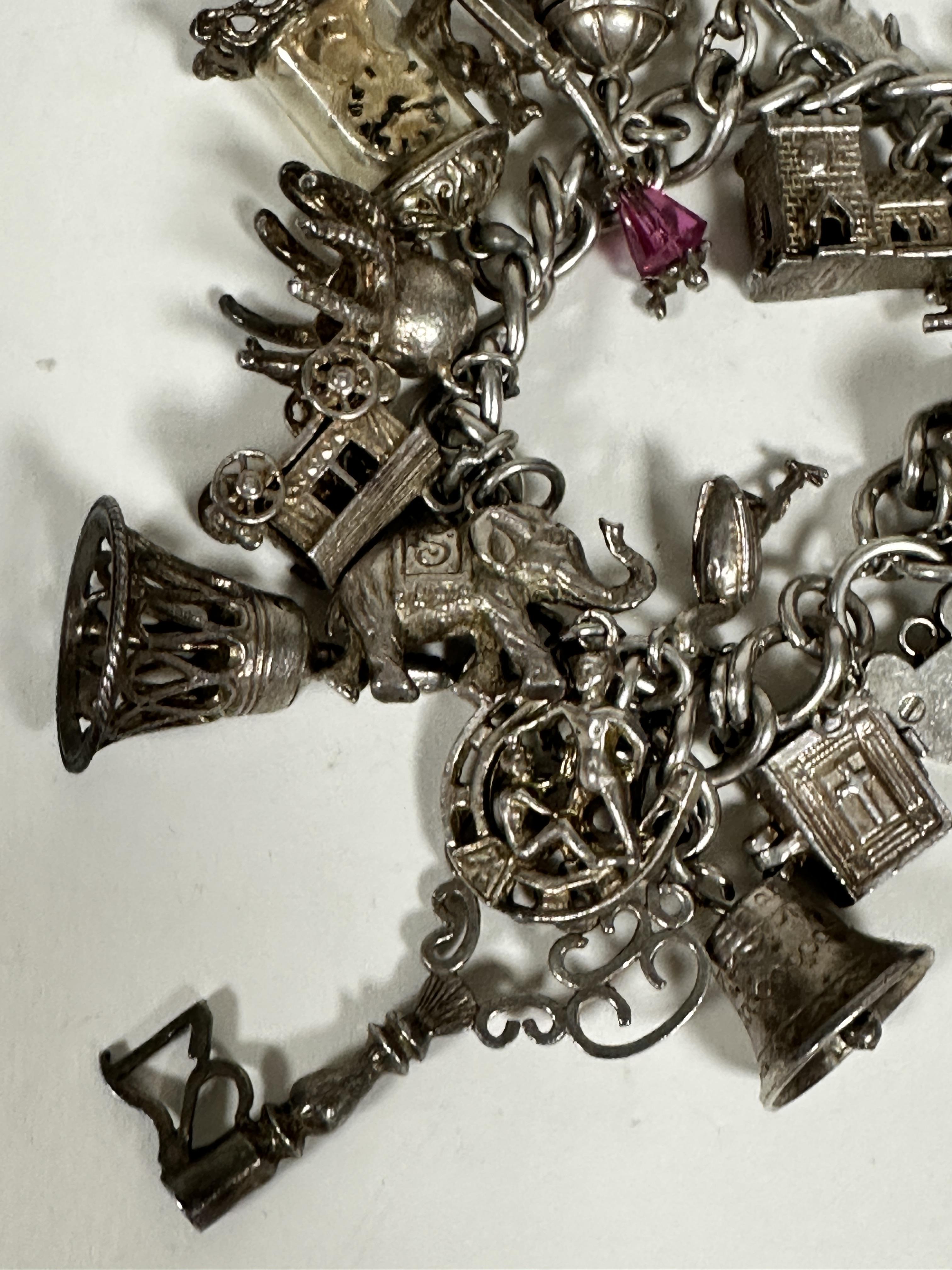A silver curb link bracelet mounted with a large collection of silver charms including a key, bells, - Image 3 of 4
