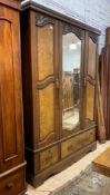 A late Victorian walnut triple wardrobe, the centre bevelled mirror door flanked by two figured