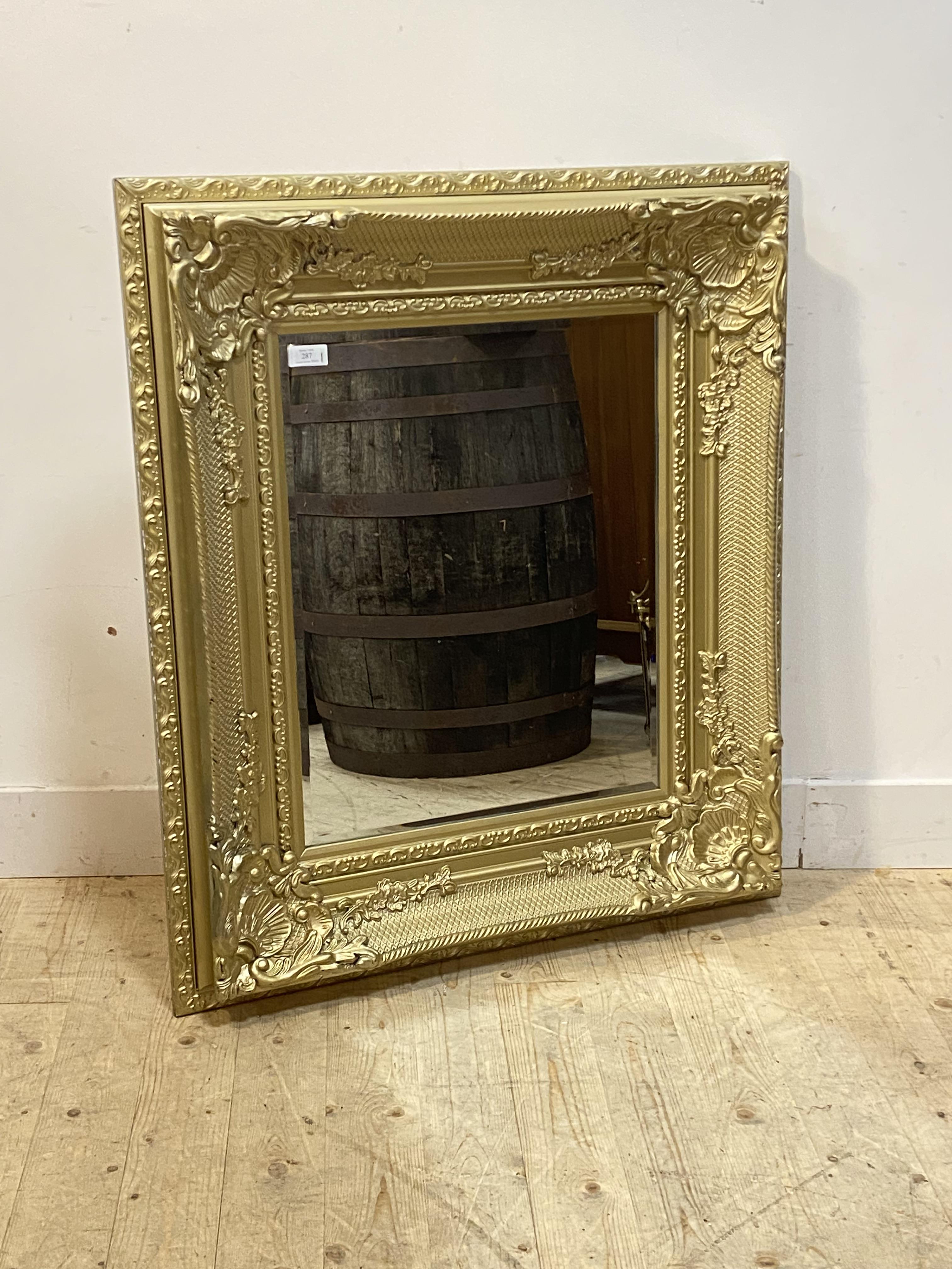 An ornate gilt framed wall mirror in the Rococo style, each corner decorated with shells and