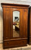 A Victorian mahogany wardrobe, the projecting cornice over arched glazed mirror door enclosing