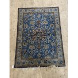 A Persian hand knotted Tabriz rug, the blue field with trailing lotus heads, within an ivory