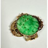 A yellow metal open work panel sided brooch. (4cm x 3.5cm) set pale green jadeite carved centre