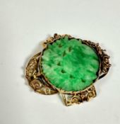 A yellow metal open work panel sided brooch. (4cm x 3.5cm) set pale green jadeite carved centre