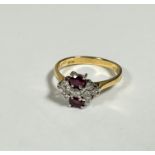 An 18ct yellow gold two stone ruby and diamond cluster ring, approximately 0.04ct, set nine