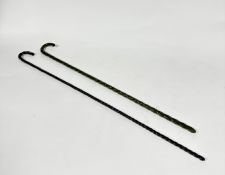 An Edwardain green spiral stem glass cane (L: 74cm) and a brown spiral glass cane (L: 82cm) (2)