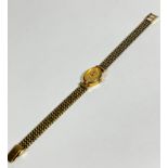 A lady's Accurist 9ct gold oval wrist watch on 9ct gold chain link bracelet with gilt dial and baton