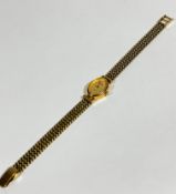 A lady's Accurist 9ct gold oval wrist watch on 9ct gold chain link bracelet with gilt dial and baton