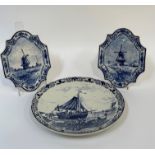 A trio of Delft wall hanging decorative plates, a pair depicting a Holland windmill scene and the