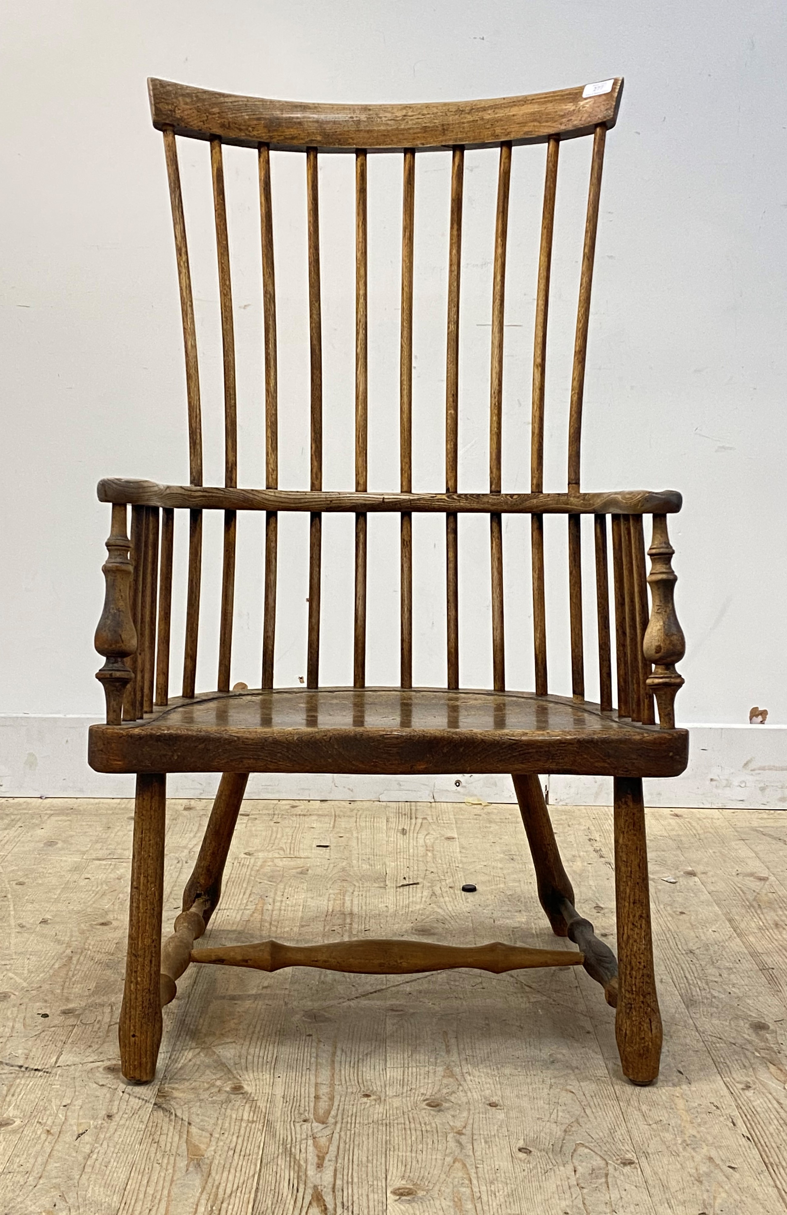A vernacular early 19th century ash and elm Windsor comb back chair, the bowed armrest with scrolled