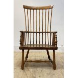 A vernacular early 19th century ash and elm Windsor comb back chair, the bowed armrest with scrolled