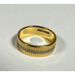 An unusual 18ct gold ribbed wedding band with central white gold stripe, (J) (4.45g)