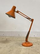 A vintage anglepoise lamp with orange finish, conical shade and stepped circular base