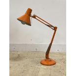 A vintage anglepoise lamp with orange finish, conical shade and stepped circular base