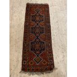 A hand knotted Turkish runner rug, the red field with pole medallion framed within a guarded