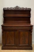 A mid 19th century figured mahogany chiffonier, with pierced fret carved pediment over two open