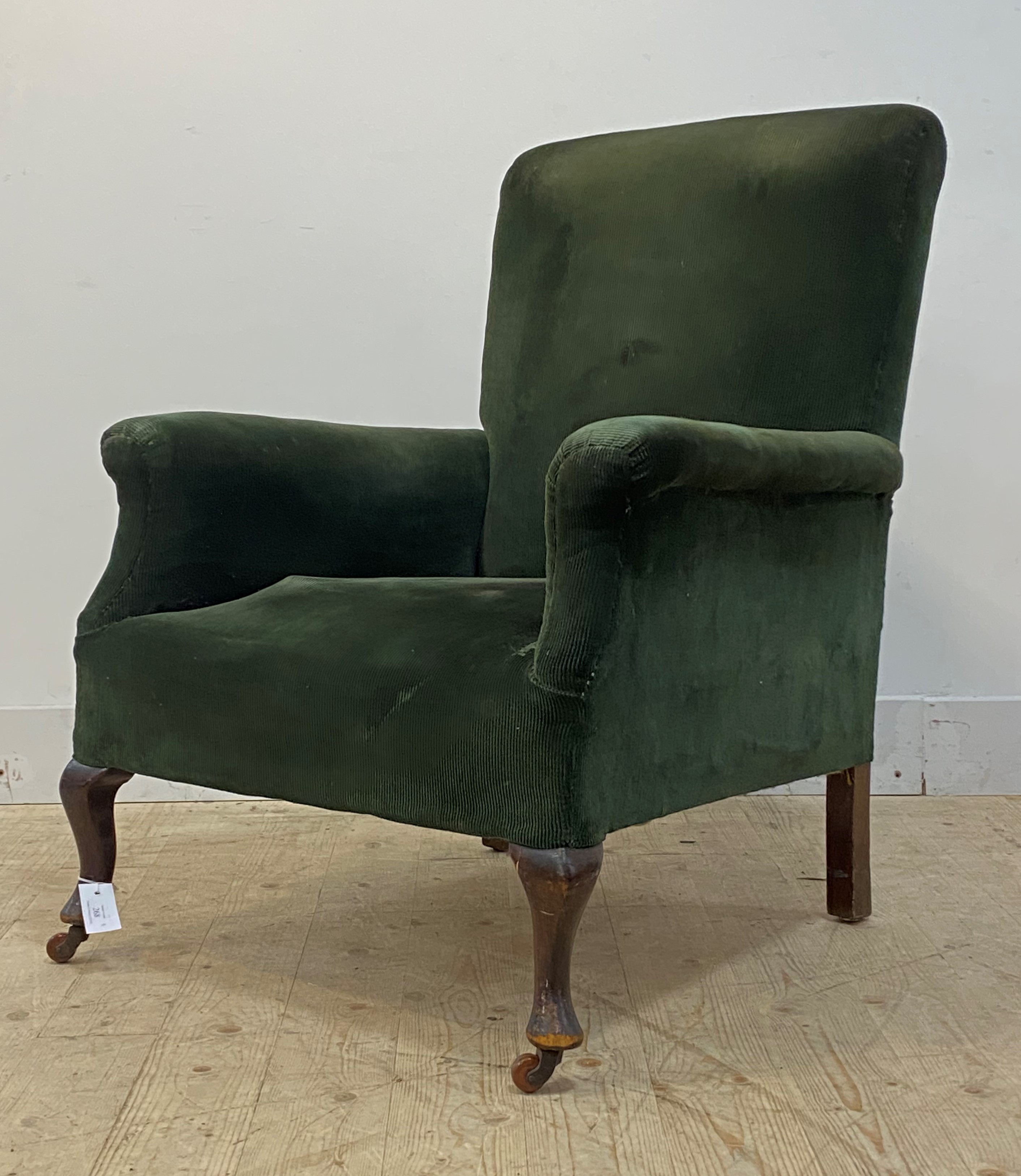 An early 20th century easy chair, upholstered in bottle green corduroy, raised on front cabriole