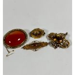 A Victorian yellow metal carnelian oval mounted brooch with scrolling border complete with safety