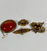 A Victorian yellow metal carnelian oval mounted brooch with scrolling border complete with safety
