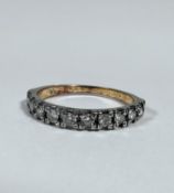 A yellow metal half eternity style ring set nine diamonds mounted in claw setting, each stone