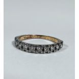 A yellow metal half eternity style ring set nine diamonds mounted in claw setting, each stone