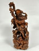 A Chinese carved Rootwood figure modelled as a wise man with dragon carved staff and carrying a