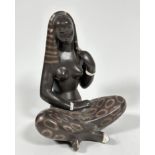 A mid century pottery seated Asian figure draped with headdress and sarong style skirt, with white