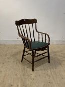 An early 20th century oak desk chair, bobbin turned spindle back over upholstered seat, raised on