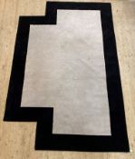 A contemporary rug of geometric form, the ivory field enclosed by a contrasting border 383cm x