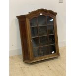 An early 20th century glazed walnut wall hanging cabinet, the door opening to three shelves,