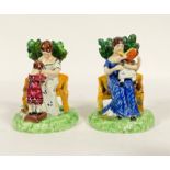 A pair of early 19th century Staffordshire lead glazed pearlware figures, each formed as a seated