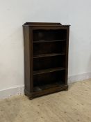 A 1930's oak three tier oak open bookcase with carved pilasters, raised on bun supports, one support