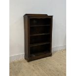 A 1930's oak three tier oak open bookcase with carved pilasters, raised on bun supports, one support