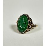 An 18ct gold dress ring set oval relief carved jadeite carved panel (2cm x 1cm) mounted in open work
